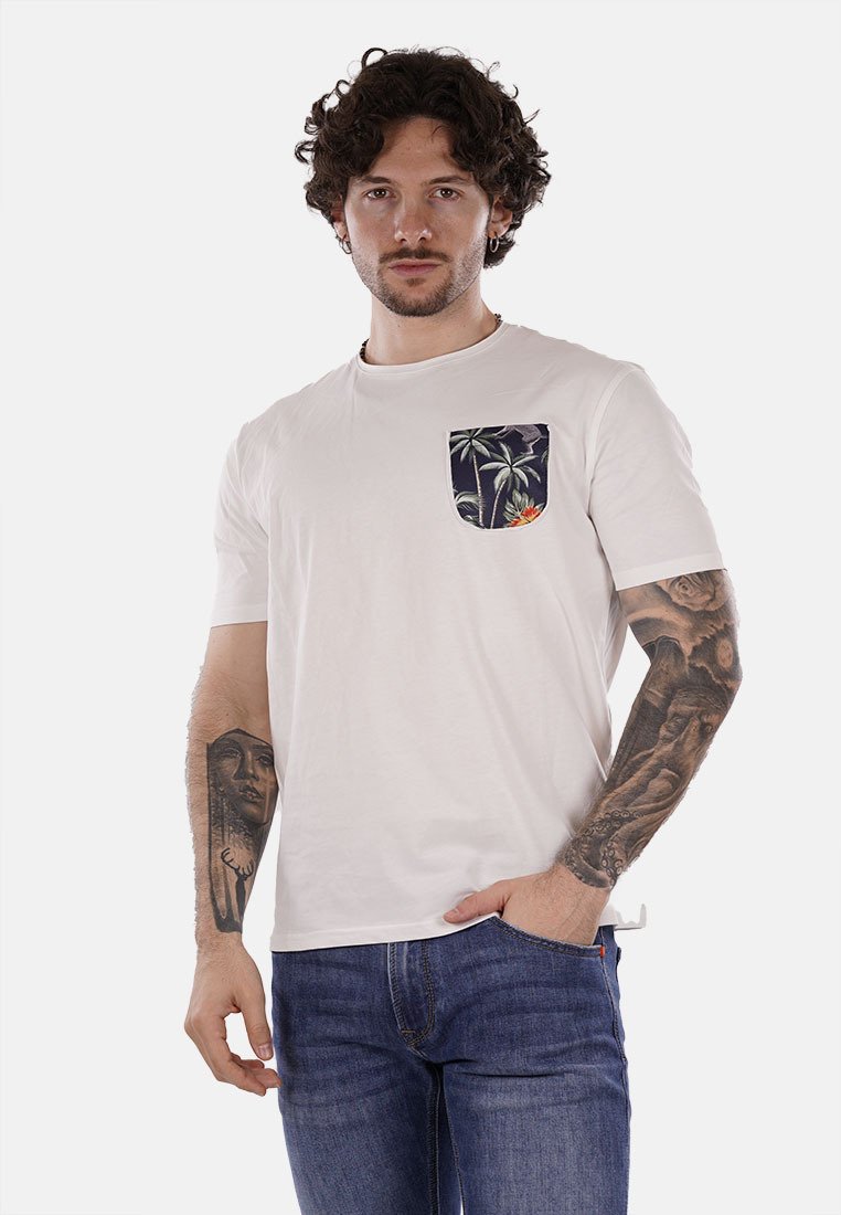 Camiseta blanca de manga corta hecha de algodón, con un bolsillo azul con un patrón de palmeras, combinada con jeans de mezclilla azules.
