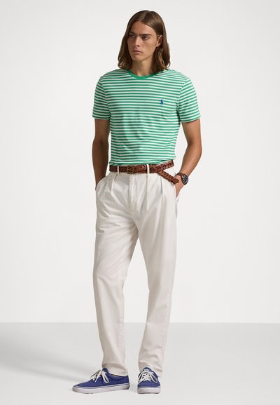 Πράσινη και λευκή ριγέ μπλούζα, λευκά παντελόνια, πλεγμένη καφέ ζώνη, μπλε αθλητικά παπούτσια. Casual ντύσιμο με άνετη εφαρμογή και κλασικό σχέδιο.