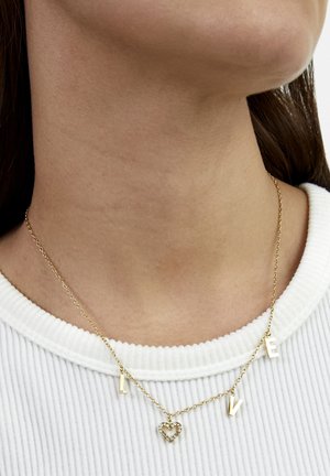 Goldkettchen mit den Buchstaben "L", "O", "V", "E" und einem Herzanhänger. Das Design ist filigran mit einem strukturierten Glieder-Muster.