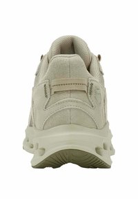 Beige mokasyni nahkaa, joissa on pehmustettu kaulus, vetotappi kannassa ja paksu pohja nähtynä takaa.