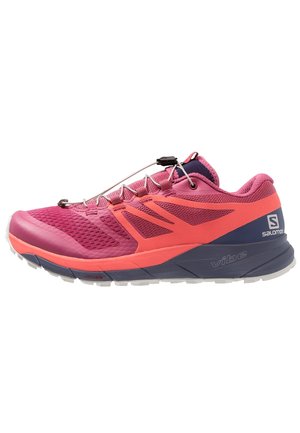 Chaussure de trail running rose vif et corail avec une semelle marine, un système de laçage rapide et des logos de la marque sur le talon et la semelle intermédiaire.
