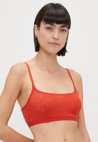 Textúrált anyagból készült piros bralette, finom mintázattal, vékony pántokkal és széles alsó szegéllyel, modern illeszkedést biztosít.