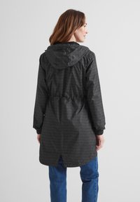 Black lightweight jacket with a hood, drawstring waist, elastic cuffs, and subtle geometric pattern. Open vent at the back for breathability.