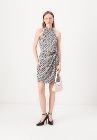 Floral halter-neck dress with a knotted detail, featuring a black background and white, pink, and yellow patterns. Paired with a light pink handbag.