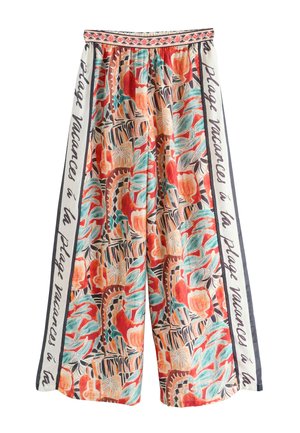 Széles szárú nadrág piros, türkiz és bézs színű színes absztrakt trópusi mintával, fehér oldalsó panelekkel, melyeken francia szöveg olvasható, valamint mintás derékrésszel.