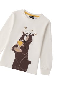 Koszulka z długim rękawem w kolorze kremowym, przedstawiająca kreskówkowego misia trzymającego słoik miodu, z pszczołami ilustrowanymi wokół misia.