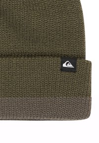 Knitted beanie in dark olive green, featuring a contrasting gray fold at the bottom and a small black and white logo tag on the side.