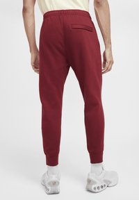 Burgundy sweatpants with an elastic waistband and cuffed ankles, featuring a back pocket and smooth cotton blend fabric.