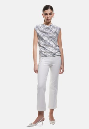 Witte mouwloze top met een blauw geruit patroon, gecombineerd met witte aansluitende broek en crèmekleurige puntige hakken. Een gladde textuur overal.