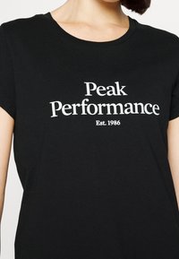 Černé tričko z bavlny s krátkým rukávem, na přední straně s bílým potiskem "Peak Performance" a "Est. 1986".