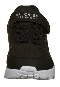Scarpa sportiva nera con tomaia strutturata, lacci e una striscia a strappo. Suola in gomma bianca con battistrada a motivo. Logo argentato sulla linguetta.
