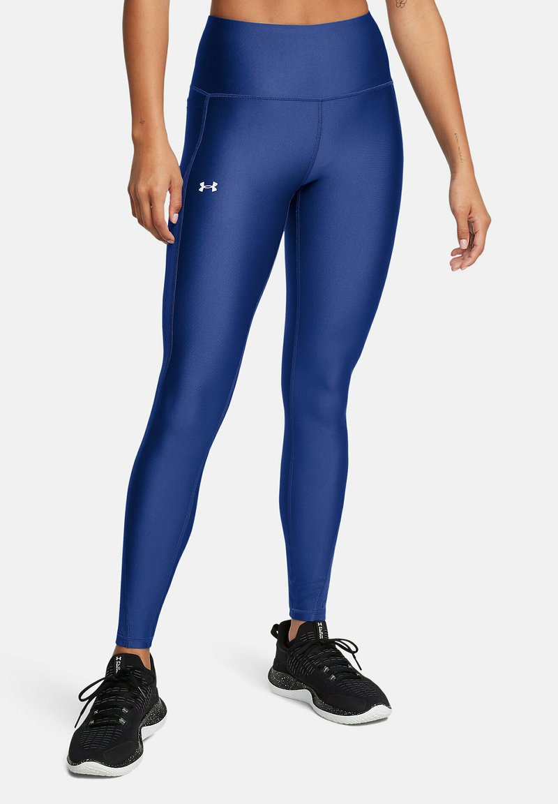Leggings de talle alto azules, fabricadas con una tela suave y elástica, que cuentan con un logo sutil en el muslo y están diseñadas para uso atlético.