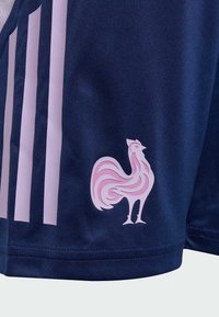 Navy soccer shorts featuring three white stripes and a pink stylized rooster logo on the lower front panel. Lightweight, textured fabric.