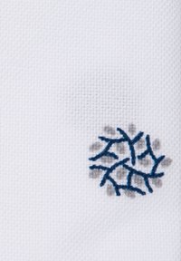 Biała tkanina z teksturowanym wzorem z niebieskimi haftowanymi detalami przypominającymi rozgałęzione linie lub płatki śniegu.