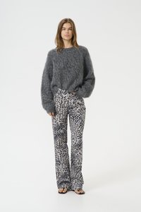 Maglione grigio fluffy con una vestibilità ampia e maniche lunghe, abbinato a pantaloni flare in stampa leopardata beige con vita alta e texture liscia.