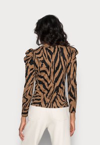 Maglia a maniche lunghe marrone con strisce nere a forma di tigre, che presenta spalle gonfiate e un design aderente. Texture in maglia morbida, adatta per un look casual.