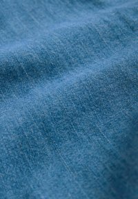 Blått texturerat tyg med en slät yta och subtilt vävt mönster. Materialet verkar lätt och hänger i mjuka veck.