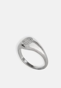 Ez egy ezüstgyűrű sima, fényes felülettel és egy kerek, gravírozott díszítéssel a tetején, amely díszes mintákkal és gyöngyös szegéllyel rendelkezik.