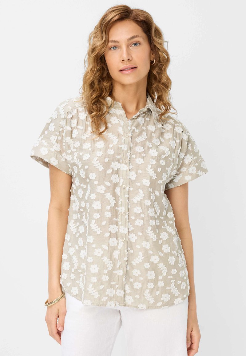 Korte mouw shirt van lichtbeige stof met witte bloemenborduring, voorzien van een knoopsluiting aan de voorkant en een relaxte pasvorm.