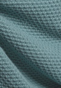 Strukturierter blauer Stoff mit einem gewebten Muster, das eine weiche, leicht erhabene Oberfläche und ein leichtes, luftiges Erscheinungsbild zeigt.