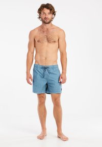 Shorts de bain en denim bleu avec une taille élastique, fermeture à cordon de serrage et un patch logo circulaire sur la jambe gauche.