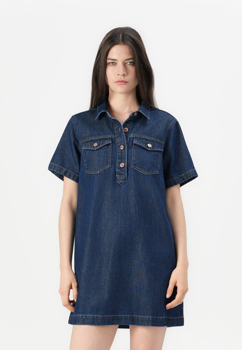 Denim shirt jurk in donkerblauw, met een knoopsluiting aan de voorkant, twee borstzakken, korte mouwen en een ontspannen pasvorm. Gladde textuur.