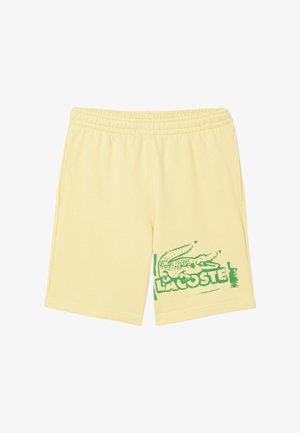 Shorts en coton jaunes avec un logo de crocodile vert et le texte "LACOSTE" sur le côté gauche. Présentent une taille élastique et des poches latérales.