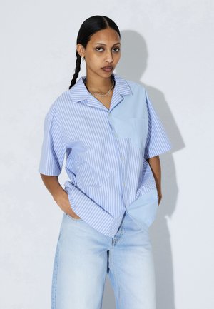 Kurzarmhemd mit Kragen, das ein gestreiftes Muster in Hellblau und Weiß aufweist, mit einem einfarbigen hellblauen Einsatz auf einer Seite und einer Brusttasche.