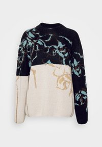 Pull en tricot avec un design en bloc de couleurs noir et beige, orné de motifs floraux en bleu et marron. Col rond, manches longues, texture douce.