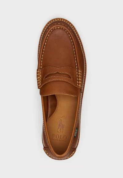 Brune lærloafers med stikninger, afrundet tå og en dekorativ rem på forsiden. Har logo innvendig og på siden.