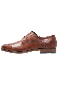 Chaussure habillée en cuir marron à lacets avec motif perforé, finition lisse, bout arrondi et talon empilé. Présente un branding minimal sur le côté.