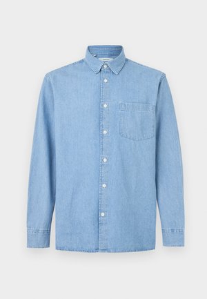 Chemise en denim bleu clair à manches longues avec une poche avant, une fermeture à boutons et un col classique sur fond blanc.
