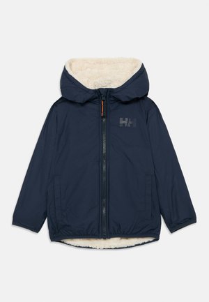 Giacca blu navy con cappuccio foderato in pelliccia, chiusura con zip, orlo elastico e tasche laterali. Presenta un dettaglio con logo sul petto.