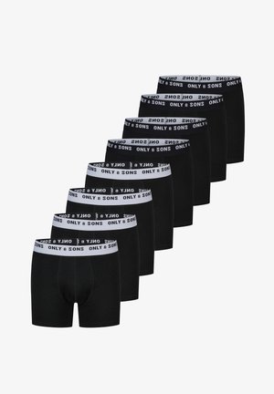 Acht paar zwarte herenslipjes met witte taillebanden met daarop "ONLY & SONS" branding in zwarte tekst.