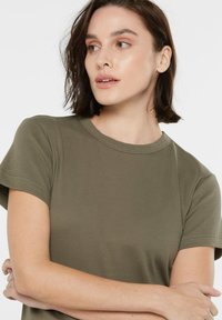 Olive green crew-neck t-shirt with short sleeves, made from smooth cotton, featuring subtle stitching details and a relaxed fit.