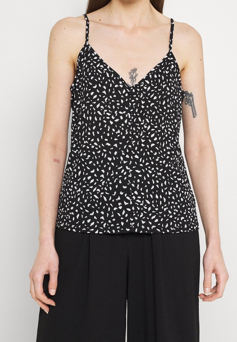 Musta ilmanhiha toppi valkoisella abstraktille kuviolle, v-kaula-aukolla, ohutolkaimilla ja rennolla leikkauksella, valmistettu kevyestä kankaasta.