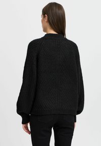 Zwarte gebreide trui met een gestructureerd patroon, geribbelde manchetten en een ronde halslijn. Heeft een ontspannen fit en een cropped lengte bij de taille.