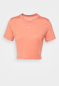 Zkrácený korálově růžový T-shirt Nike s krátkým rukávem a malým bílým logem Nike swoosh uprostřed přední strany.