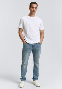 Camiseta de algodón blanca, jeans de mezclilla azul claro, zapatillas blancas. Corte casual, sin patrones, textura suave y un diseño simple.