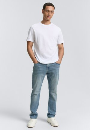 Camiseta de algodón blanca, jeans de mezclilla azul claro, zapatillas blancas. Corte casual, sin patrones, textura suave y un diseño simple.
