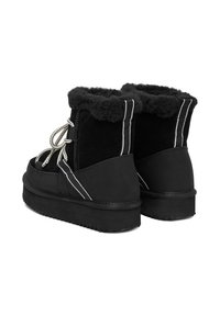 Fekete bokacsizmák puha, műszőrme díszítéssel. Ellentétes fehér vonalakkal és textúrázott cipőfűzőkkel tervezve, masszív platform talppal.