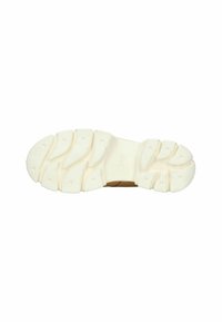 La suela del zapato presenta una base de goma blanca con un patrón de agarre texturizado, ranuras multidireccionales y un pequeño logo cerca del talón.