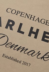 Beige tekstiili, jossa on suuria mustia kirjaimia: "COPENHAGEN", "BARLHE" ja "Denmark". Alempana teksti "Established 2017." Sileä pintatekstuuri.