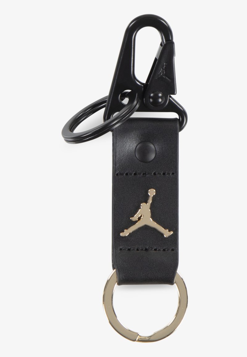 Black leather keychain with a gold Jumpman logo, featuring a gold ring and black clip for attachment. Smooth texture with subtle stitching detail.