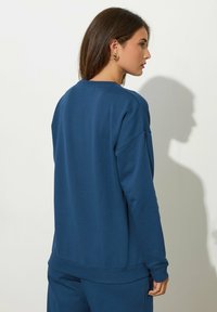 Felpa blu navy con vestibilità comoda, polsini e orlo a coste. Texture liscia, design minimale e collo rotondo.