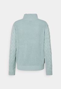 Ljusblå stickad jumper med hög krage, ribbad nederkant och flätstickat mönster på ärmarna. Mjuk textur och avslappnad passform.