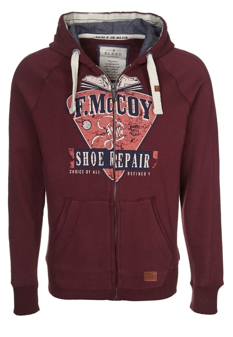 Sudadera con cremallera de color burdeos, fabricada en una mezcla de algodón. Presenta un estampado gráfico, dos bolsillos frontales y un cordón en contraste en la capucha.