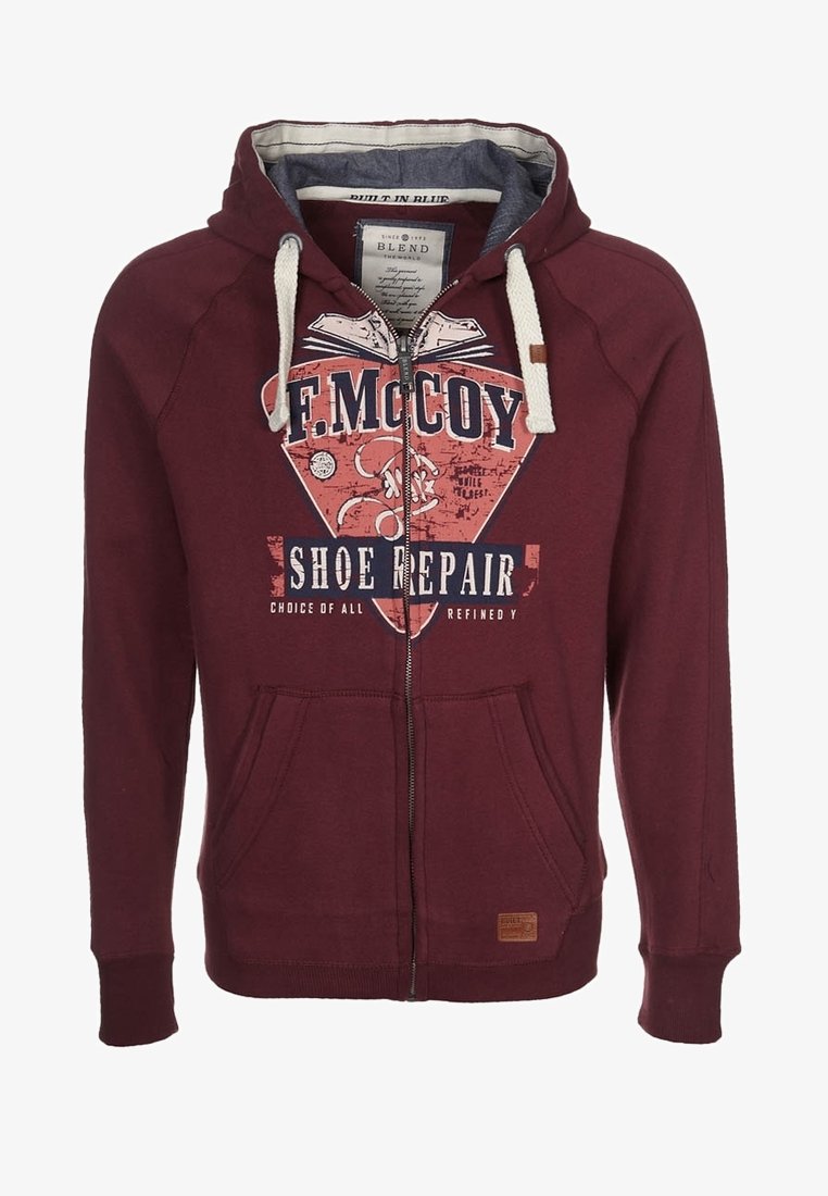Sudadera con cremallera de color burdeos, fabricada en una mezcla de algodón. Presenta un estampado gráfico, dos bolsillos frontales y un cordón en contraste en la capucha.
