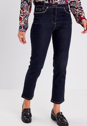 Dark blue denim jeans with a slim fit, featuring a high waist, contrasting orange stitching, and a cropped length. Paired with black loafers.