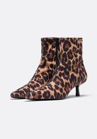 Bottes chelsea imprimé léopard en matériau doux, avec un bout pointu, un talon moyen et une fermeture éclair latérale. Motif texturé sur toute la surface.